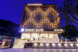 A modern hotel with a prominent 'ONEST ELITE' sign, a staircase leading to the entrance, and a well-lit facade. - O'Nest Elite (Miraj)