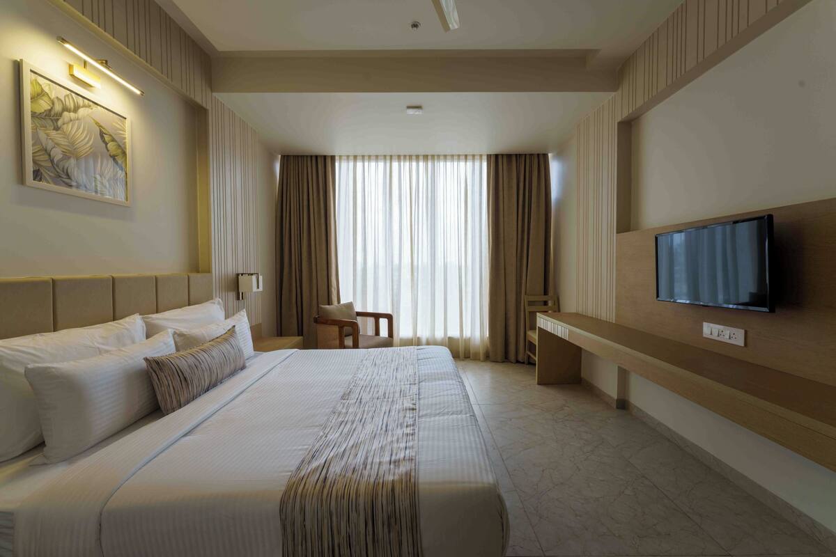 Une chambre d’hôtel avec un grand lit, un bureau, une chaise, une télévision et un tableau au mur.