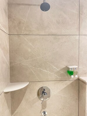 Une salle de bain avec une douche, un lavabo et un distributeur de savon.