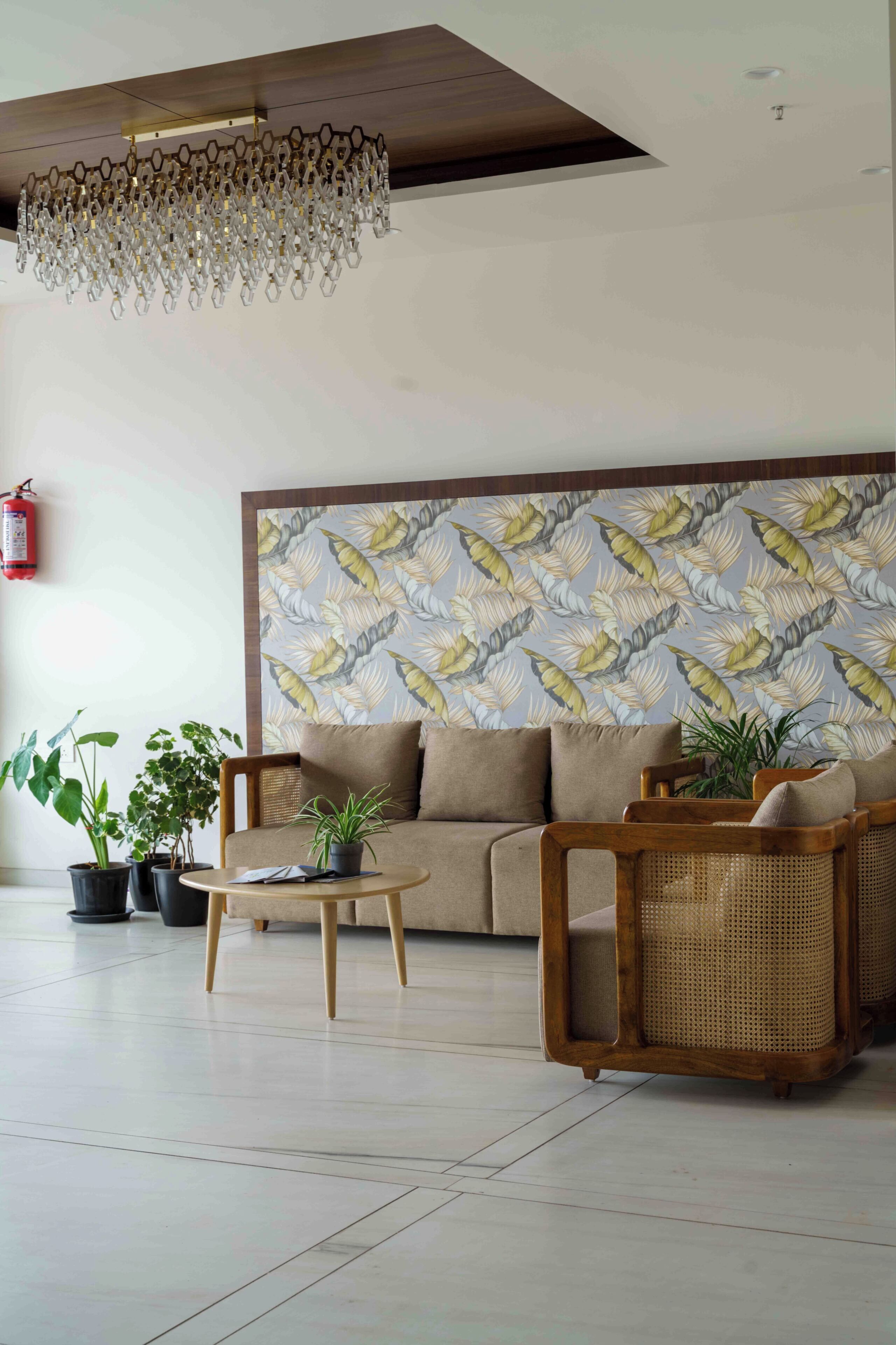 Un hall d’entrée moderne avec un ensemble de canapés, une table basse, des plantes en pot, un mur à motifs et un luminaire suspendu.