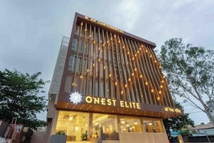 Un hotel con fachada moderna, un cartel llamativo que dice 'O'Nest Elite' y una entrada visible.