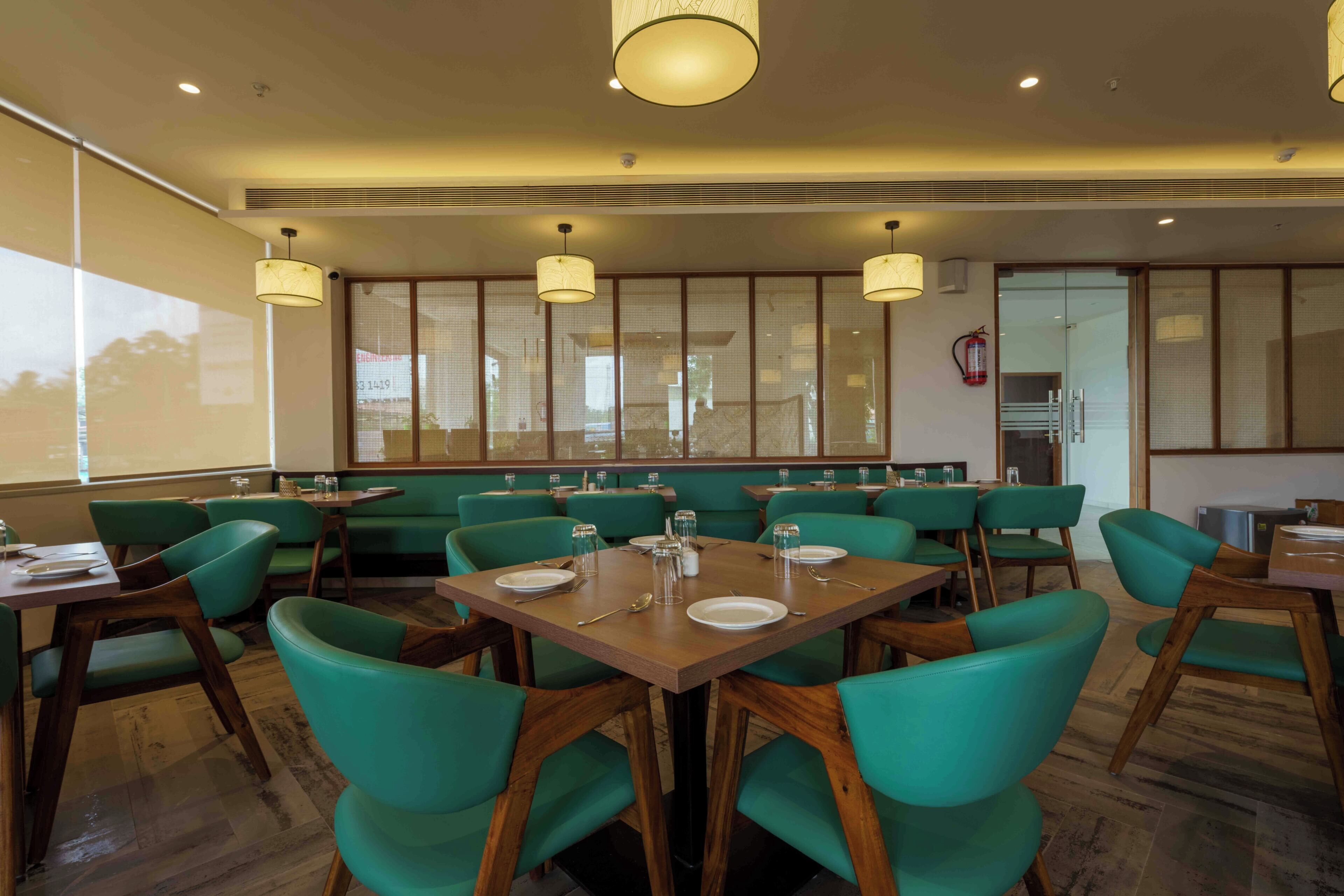 A restaurant with booths and tables, wooden flooring, and hanging pendant lights.