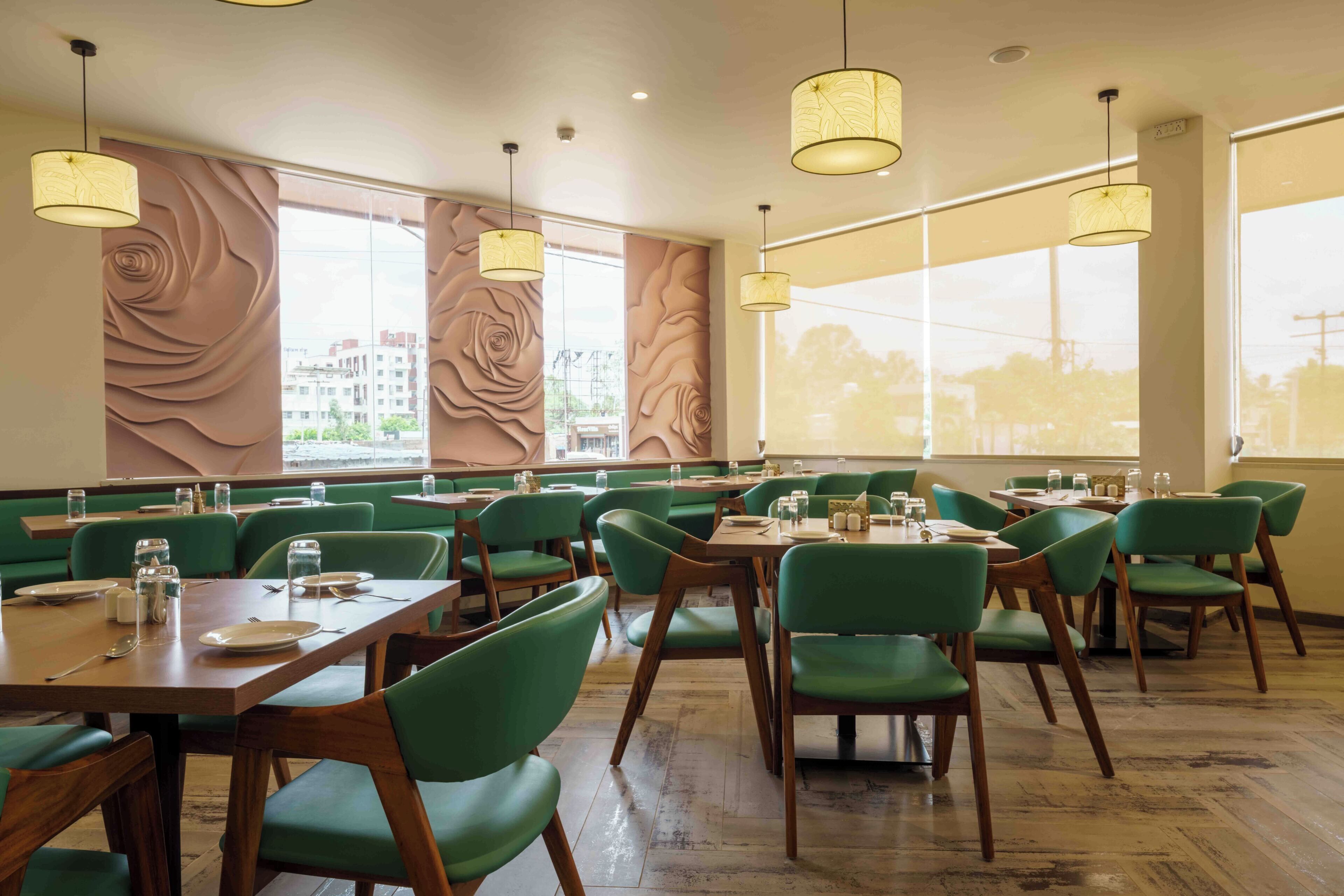 Een restaurant met groene stoelen, houten tafels en grote ramen met uitzicht op gebouwen.