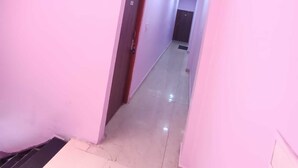 Un pasillo estrecho, bien iluminado, con piso de baldosas y una puerta al final.