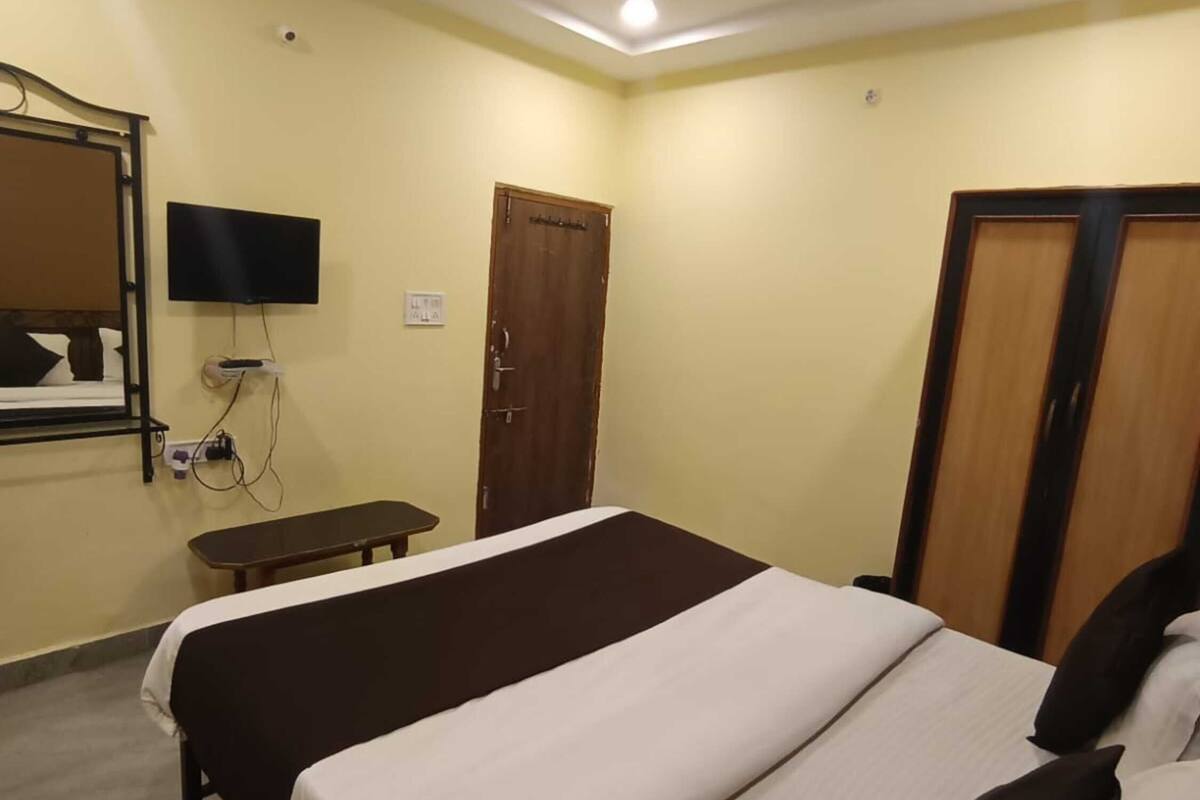 Una camera d'albergo con un letto, una scrivania, un televisore e una ventola a soffitto.