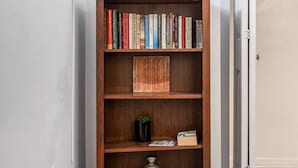 A bookshelf in a hallway with a patterned rug, a small plant, and a lantern. - 3br with Private Entrance - Garden Unit (Chicago)