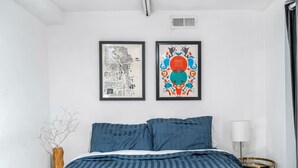 A bedroom with a bed, two framed artworks, a bedside table, and a lamp. - 3br with Private Entrance - Garden Unit (Chicago)