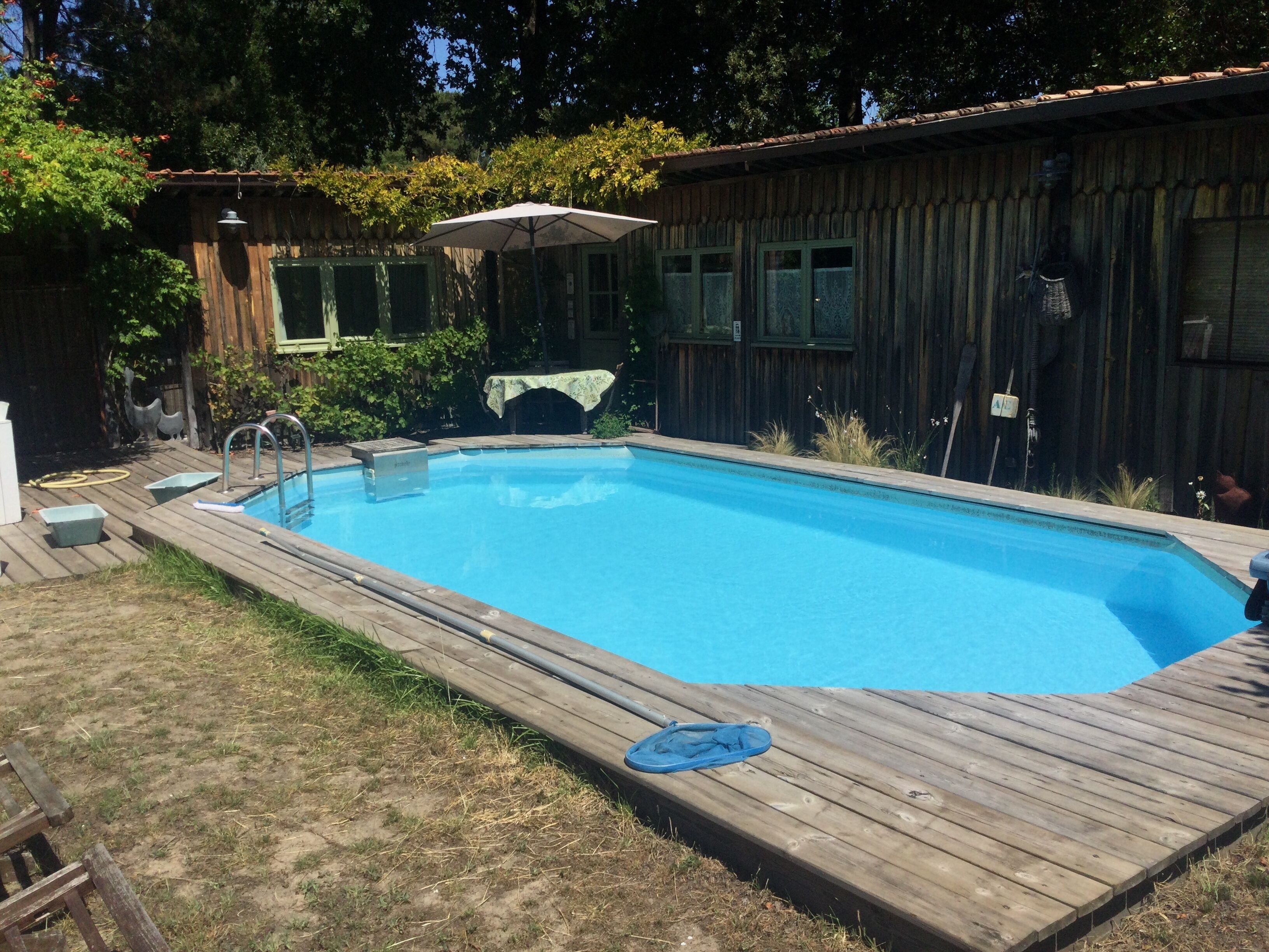 Une piscine rectangulaire entourée d’une terrasse en bois.