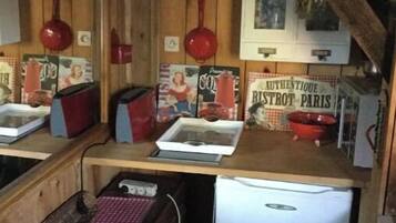 Une cuisine dotée de meubles en bois, d’un réfrigérateur, ainsi que de divers ustensiles et appareils de cuisine.