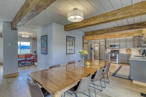 A spacious dining area with a wooden table and chairs, a kitchen with modern appliances, and a view of the outdoors.