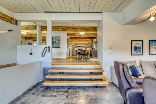 A staircase leading to a dining area with a wooden ceiling and a view of a kitchen.