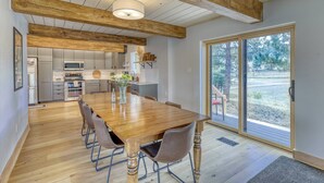 A spacious dining area with a wooden table and chairs, a kitchen in the background, and a large sliding glass door leading to an outdoor area. - Newly Remodeled Chalet with Hot Tub, Stunning Views, Minutes to Downtown Pagosa (Pagosa Springs)