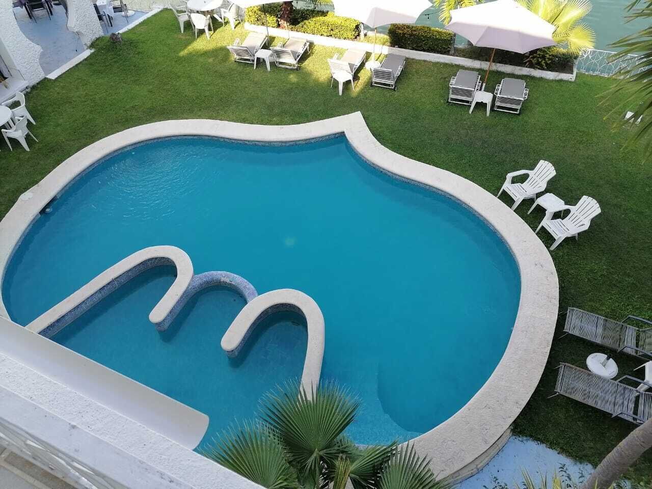 Una piscina dal design originale, circondata da confortevoli lettini e ombrelloni, con vista su un prato curato.