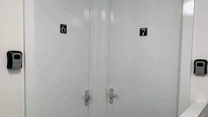 Deux portes blanches, portant les numéros 6 et 7, une petite marche menant à un palier, et un capteur fixé au mur sur la porte de gauche.