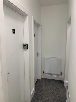 A hallway with a white door marked with the number 4, a radiator, and a carpeted floor.