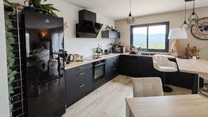 Eine moderne Küche mit schwarzen Schränken, einer Holz Arbeitsplatte und einem großen Fenster mit Blick ins Freie.