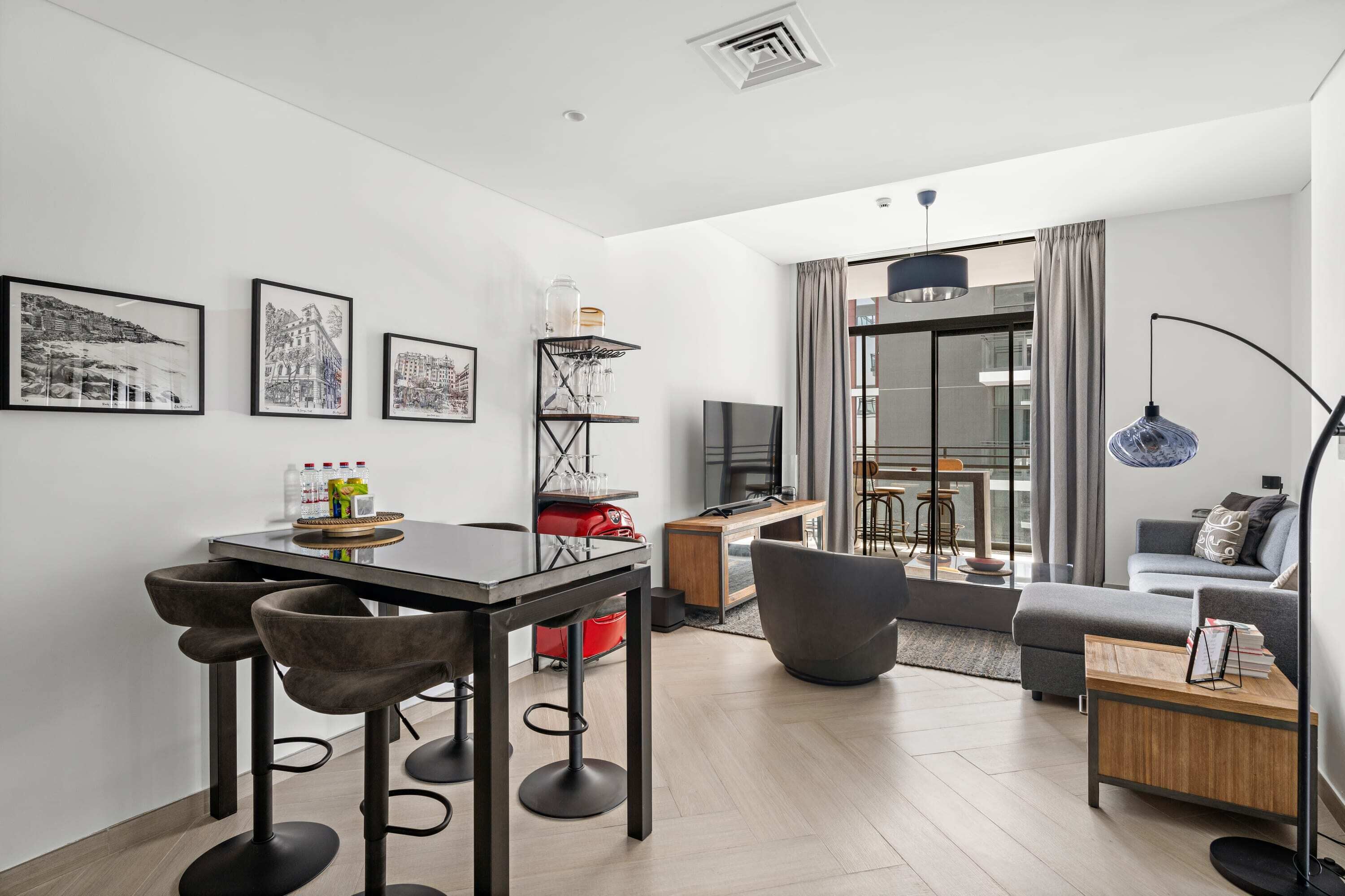 A modern living room with a dining area, a sofa, a TV, and artwork on the wall.