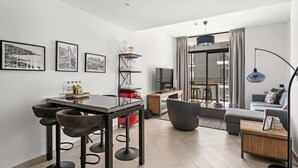 A modern living room with a dining area, a sofa, a TV, and artwork on the wall. - Wilton Park Res - Nad Al Sheba (Dubai)