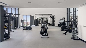 A modern gym with various exercise equipment, large windows, and a clean, spacious layout. - Wilton Park Res - Nad Al Sheba (Dubai)
