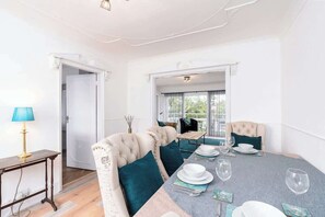 A dining area with a table set for four, a sofa with teal cushions, and a lamp on a side table.
