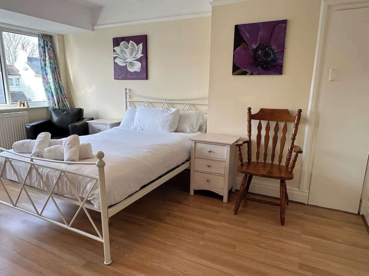 A bedroom with a bed, bedside tables, a chair, and artwork on the walls.