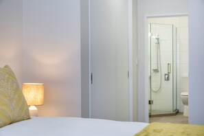 Ein Hotelzimmer mit Bett, Nachttischlampe, einer Duschkabine und Toilette.