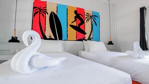 A hotel room with two beds, white bedding, a large swan-shaped towel, and a colorful wall mural featuring surfers and palm trees. - Slumber Party Beach Koh Phangan (Ko Pha-ngan)