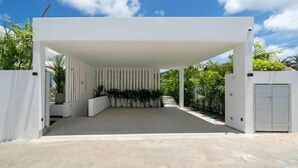 A modern covered patio area with a concrete floor, surrounded by white walls and a row of plants. - Modern Open Design 4BR Pool Villa Mina (Rawai)