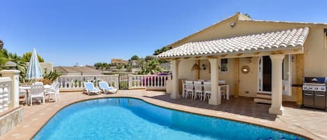 Une piscine avec des chaises longues et un espace patio couvert.