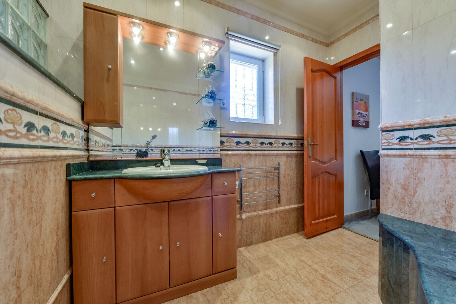 Un baño con tocador de madera, lavabo, espejo y perchero para toallas.