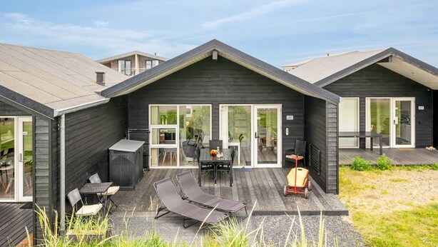 Een modern huis met een patio, compleet met een tafel, stoelen en loungestoelen.