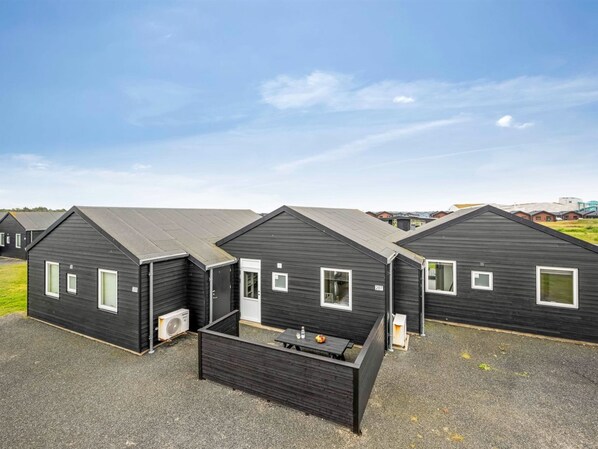 A row of modern, dark-colored cabins with a flat roof, each featuring a small window and an air conditioning unit.
