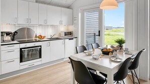 Een moderne keuken met witte kastjes, een roestvrijstalen fornuis en een ontbijt klaar gezet eethoek.