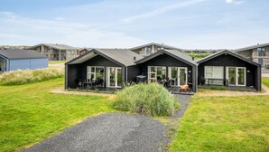Een rij moderne, donkergekleurde cabins met grote ramen en buitenzitjes.