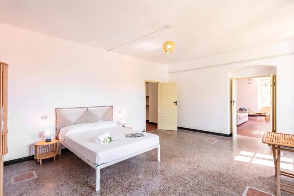 A bedroom with a bed, bedside table, lamp, and a door leading to another room. - Mulinetti Houses (Recco)