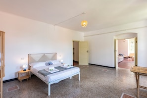 Ein Schlafzimmer mit einem Bett, Nachttischen, einer Lampe und einer Tür zu einem anderen Raum.