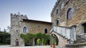 Un bâtiment historique en pierre, doté de fenêtres en arc de cercle et d’une tour.