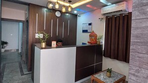 Una moderna zona de recepción con mostrador, un reloj y una pequeña mesa con una planta.