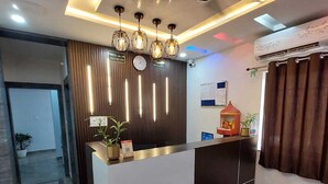 A modern reception area with a marble floor, a reception desk, a clock, and a small table with a plant.