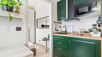 A modern kitchen with green cabinets, a microwave, and a coffee machine.