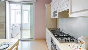 A modern kitchen with a gas stove, a microwave, and a dining area with a table and chairs. - GuestHost - Comfortable apartment located on the ground floor of a renovated building.In 110 m2 of space, it comfortably accommodates 4 people with two double bedrooms and two bathrooms.Possibility to park for free inside the property, in the courtyard ( (Rimini)
