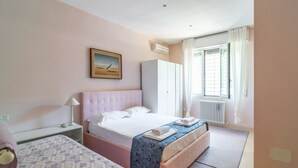 A bedroom with a bed, a bedside table, a wardrobe, a radiator, and a window with curtains. - GuestHost - Comfortable apartment located on the ground floor of a renovated building.In 110 m2 of space, it comfortably accommodates 4 people with two double bedrooms and two bathrooms.Possibility to park for free inside the property, in the courtyard ( (Rimini)