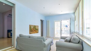 A living room with two grey sofas, a painting on the wall, and a large window with blinds. - GuestHost - Comfortable apartment located on the ground floor of a renovated building.In 110 m2 of space, it comfortably accommodates 4 people with two double bedrooms and two bathrooms.Possibility to park for free inside the property, in the courtyard ( (Rimini)