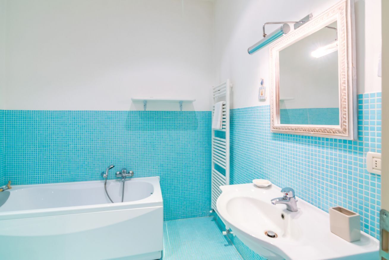 A bathroom with a bathtub, a sink, and a mirror.