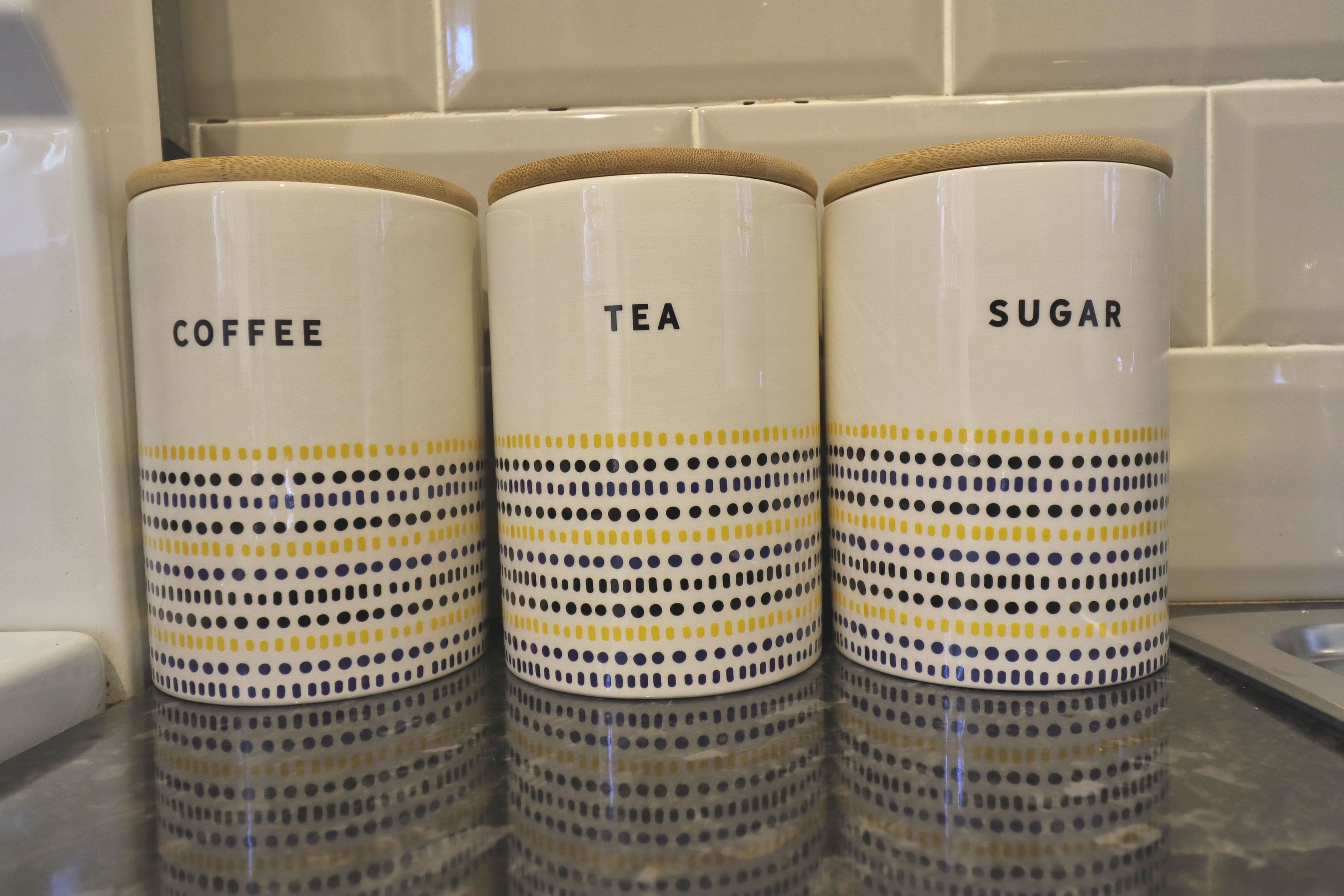 Three white containers with yellow and black polka dots labeled 'Coffee,' 'Tea,' and 'Sugar.'