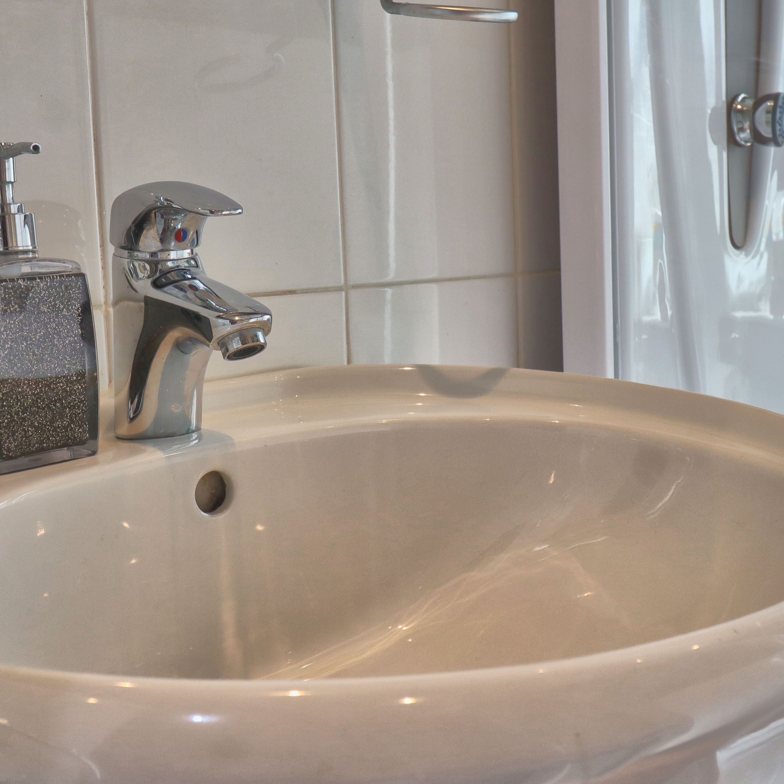 A bathroom sink with a chrome faucet and a soap dispenser.