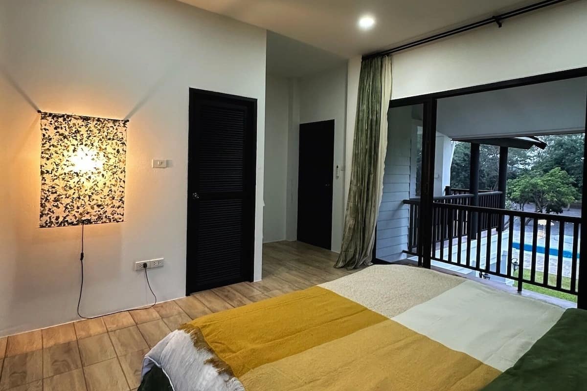 A modern bedroom with a bed, a wall-mounted light, a sliding door, and a balcony with a view.