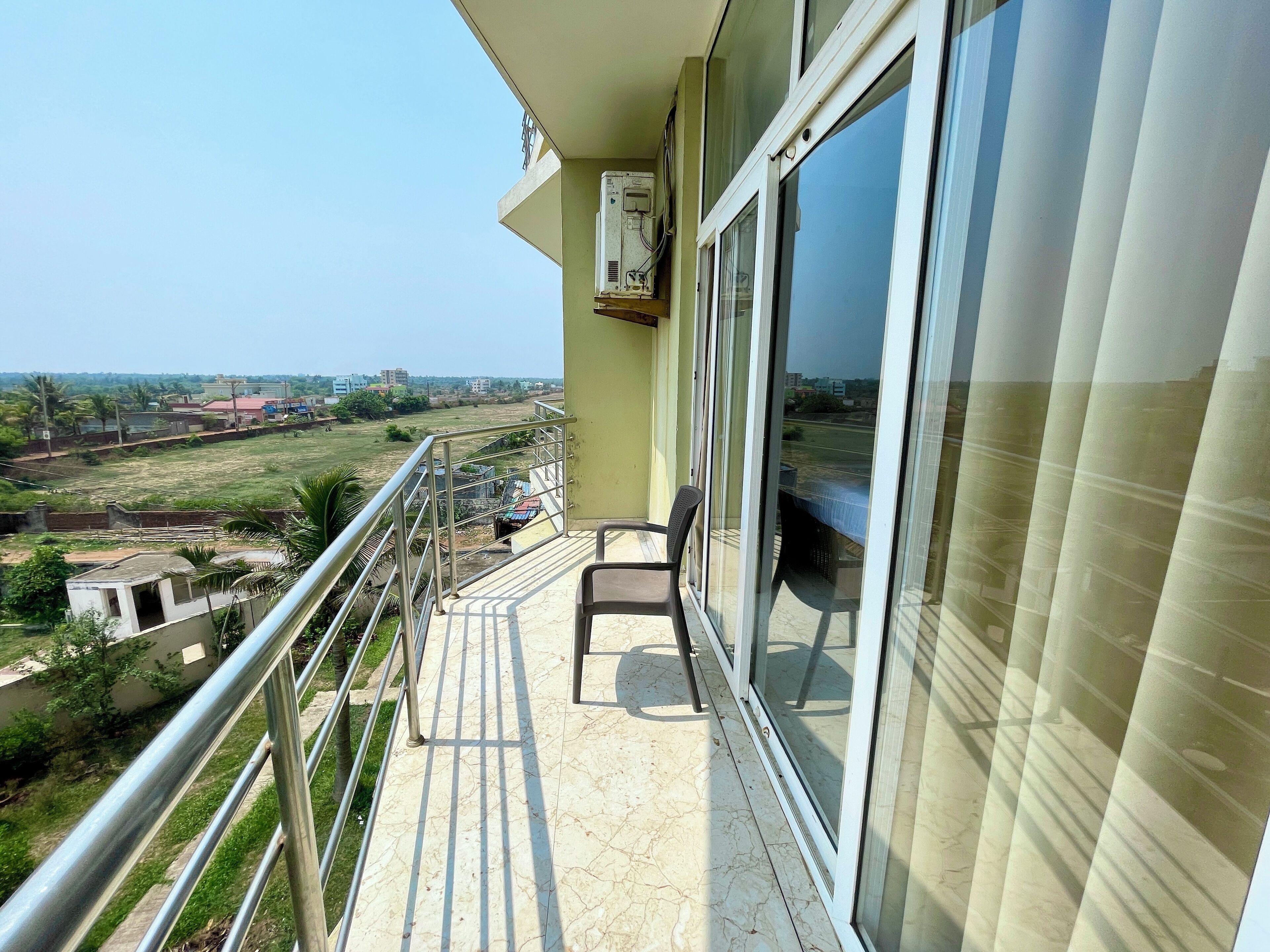 Un balcón con vista a un paisaje verde y edificios al fondo.