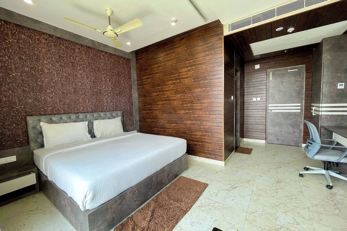 Quarto moderno com uma cama grande, um ventilador de teto e uma escrivaninha com uma cadeira.
