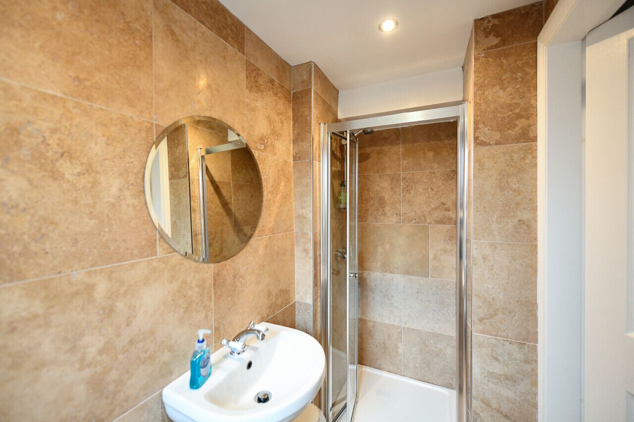 A bathroom with a sink, mirror, and shower.